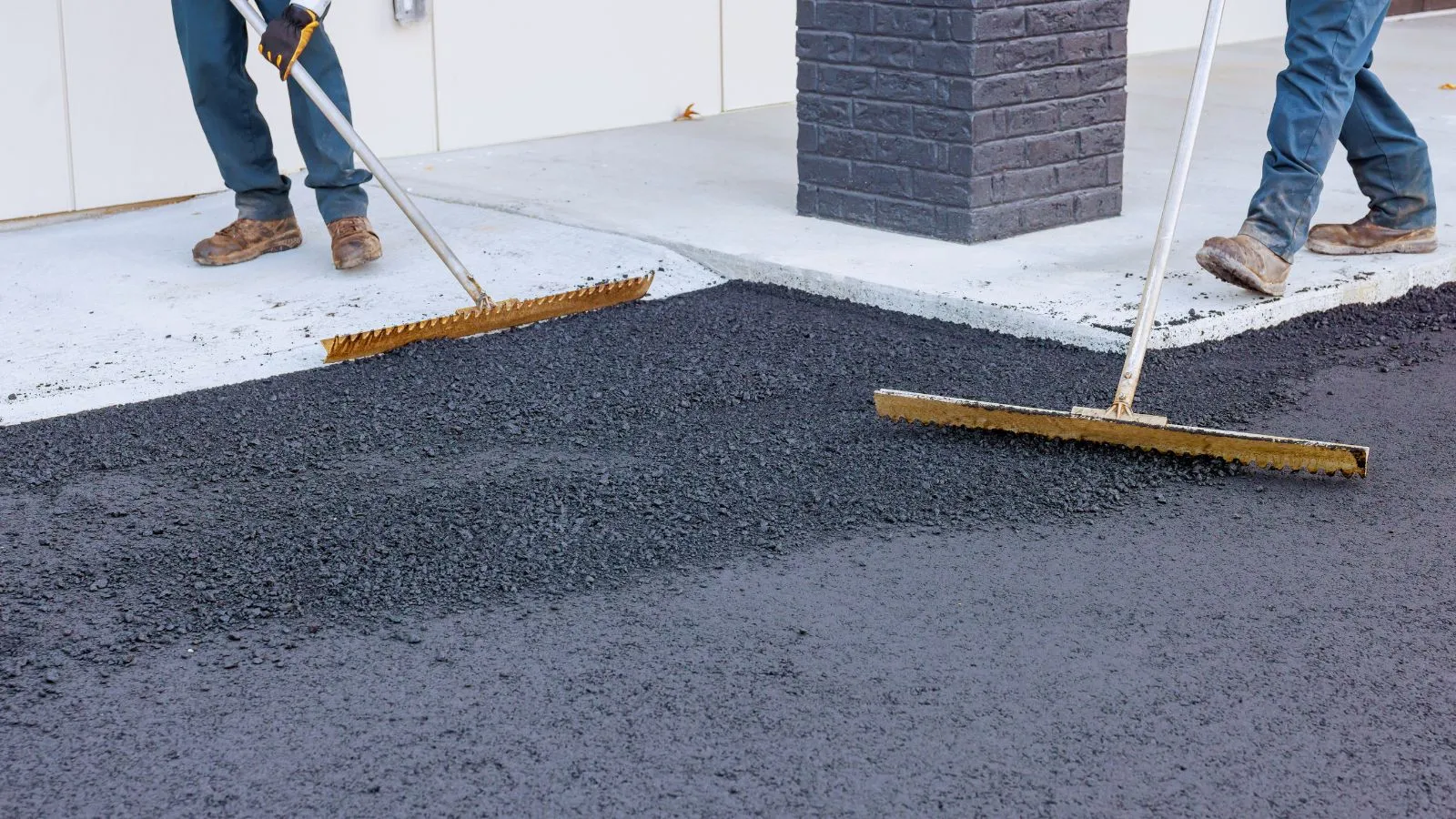 Crew works to lay fresh asphalt at construction site in residential area